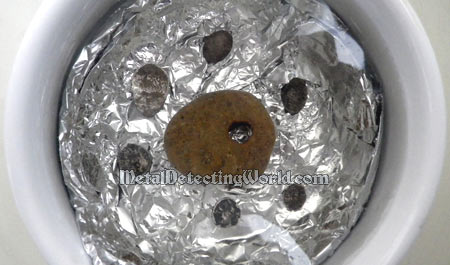 Tarnished Silver Coins Are Placed On Aluminum Foil Submerged In Electrolyte