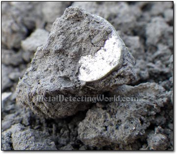 Partially Visible Wire Coin Inside the Dirt Lump